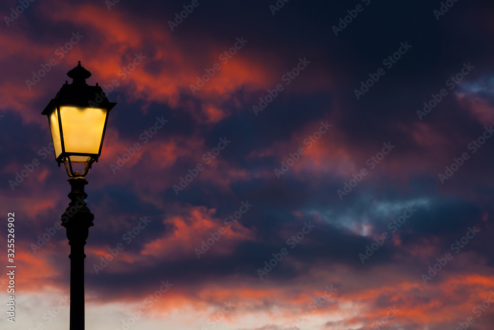 Old fashioned street lamp against beautiful sunset sky and colorful clouds (with copy space)