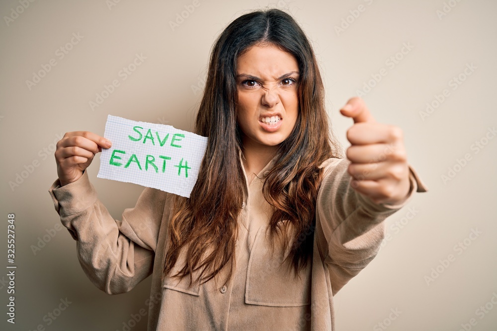 Young beautiful woman holding paper asking for save earth and enviroment conservation annoyed and frustrated shouting with anger, crazy and yelling with raised hand, anger concept Young beautiful woman holding paper asking for save earth and enviroment conservation annoyed and frustrated shouting with anger, crazy and yelling with raised hand, anger concept
