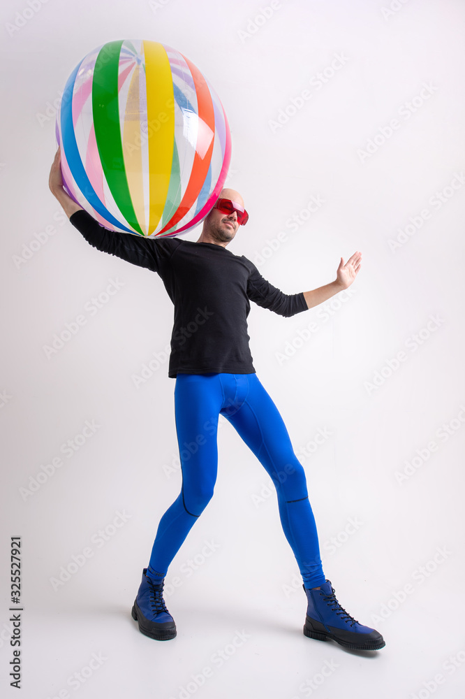 Stylish athletic man holding beach ball in his hand over white studio background