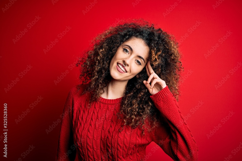 Young beautiful woman with curly hair and piercing wearing casual red sweater Smiling pointing to head with one finger, great idea or thought, good memory Young beautiful woman with curly hair and piercing wearing casual red sweater Smiling pointing to head with one finger, great idea or thought, good memory