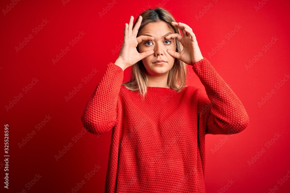 Young beautiful blonde woman wearing casual sweater over red isolated background Trying to open eyes with fingers, sleepy and tired for morning fatigue Young beautiful blonde woman wearing casual sweater over red isolated background Trying to open eyes with fingers, sleepy and tired for morning fatigue
