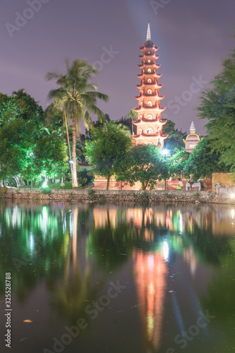 Close-up main tower of Tran Quoc Buddhist temple reflection on West Lake in Hanoi at night