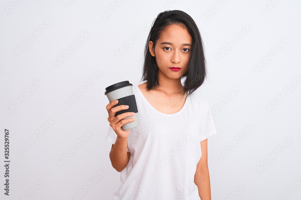 Young chinese woman drinking take away glass of coffee over isolated white background with a confident expression on smart face thinking serious Young chinese woman drinking take away glass of coffee over isolated white background with a confident expression on smart face thinking serious