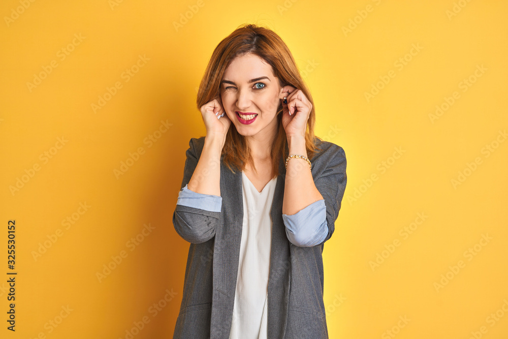 Redhead caucasian business woman over yellow isolated background clueless and confused expression with arms and hands raised. Doubt concept. Redhead caucasian business woman over yellow isolated background clueless and confused expression with arms and hands raised. Doubt concept.