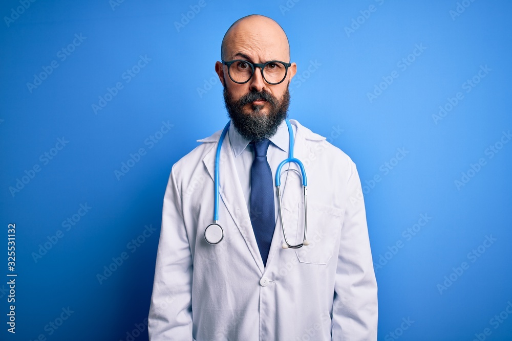 Handsome bald doctor man with beard wearing glasses and stethoscope over blue background skeptic and nervous, frowning upset because of problem. Negative person. Handsome bald doctor man with beard wearing glasses and stethoscope over blue background skeptic and nervous, frowning upset because of problem. Negative person.