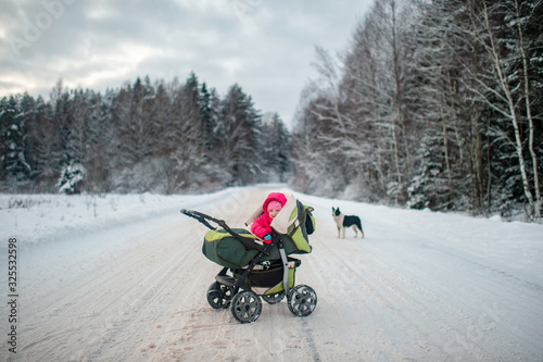A small child in a pink suit lies in a stroller in winter