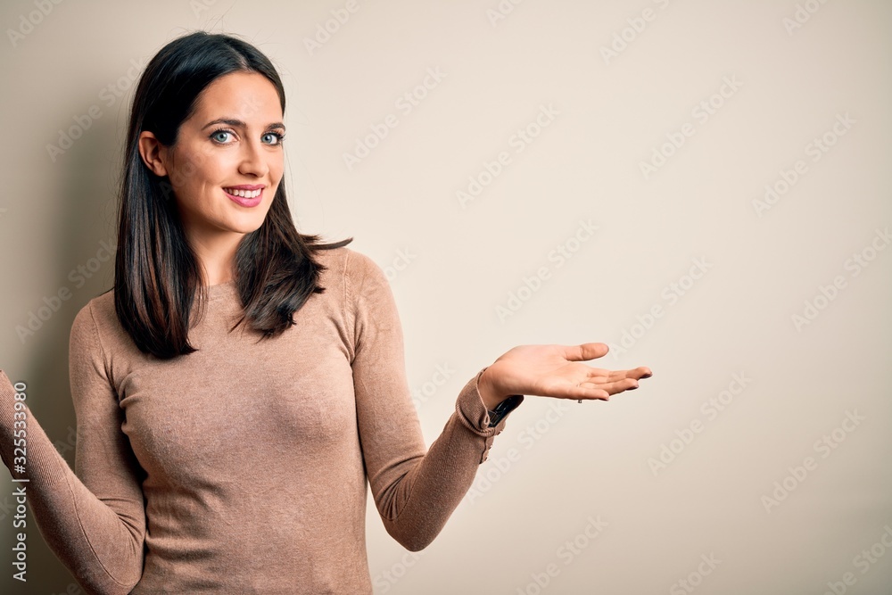 Young brunette woman with blue eyes wearing casual sweater over isolated white background smiling showing both hands open palms, presenting and advertising comparison and balance Young brunette woman with blue eyes wearing casual sweater over isolated white background smiling showing both hands open palms, presenting and advertising comparison and balance