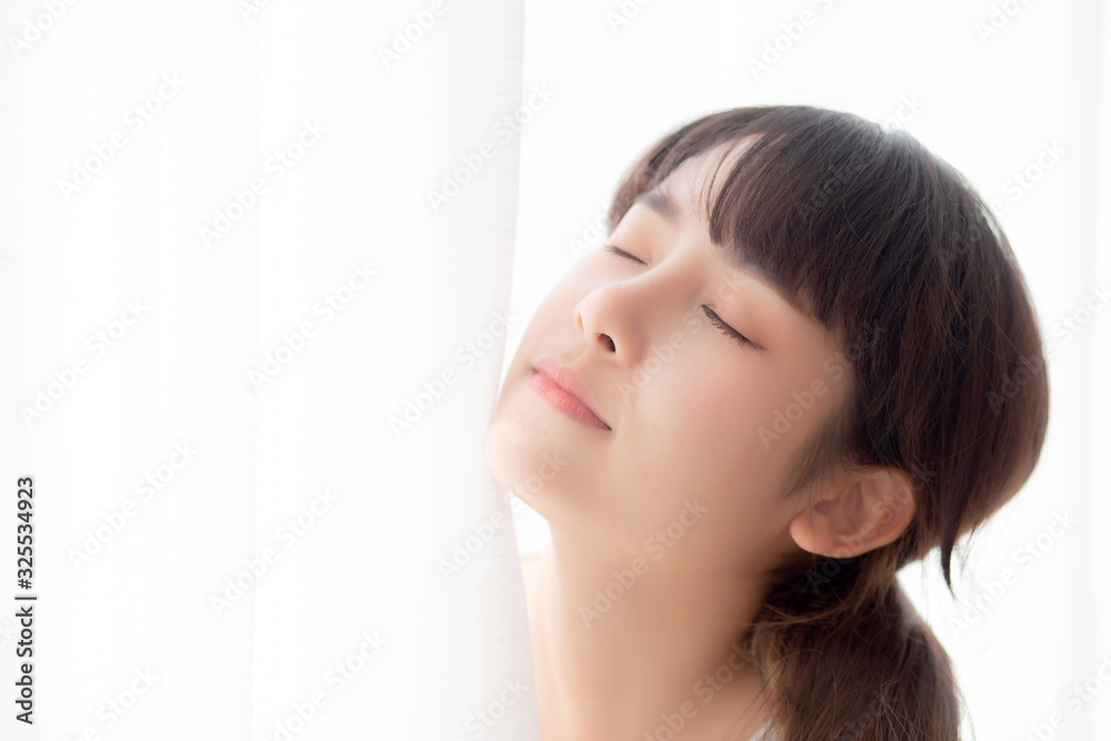 Portrait of beautiful young asian woman standing the window and smile while wake up with sunrise at morning, girl happy with freshness and cheerful, lifestyle and relax concept. Portrait of beautiful young asian woman standing the window and smile while wake up with sunrise at morning, girl happy with freshness and cheerful, lifestyle and relax concept.