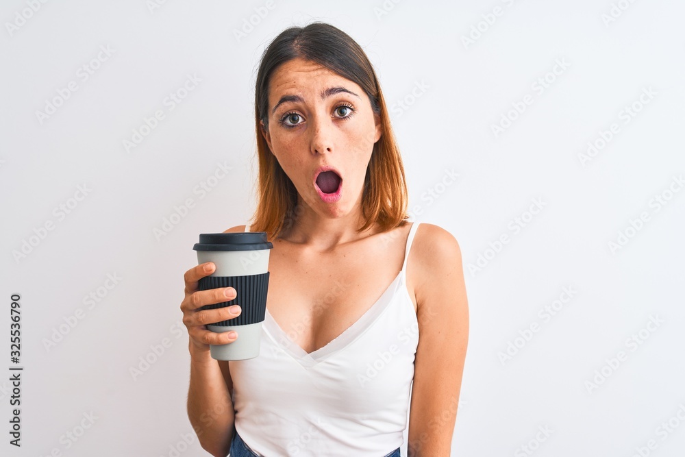 Beautiful redhead woman drinking take away coffee over isolated background scared in shock with a surprise face, afraid and excited with fear expression Beautiful redhead woman drinking take away coffee over isolated background scared in shock with a surprise face, afraid and excited with fear expression