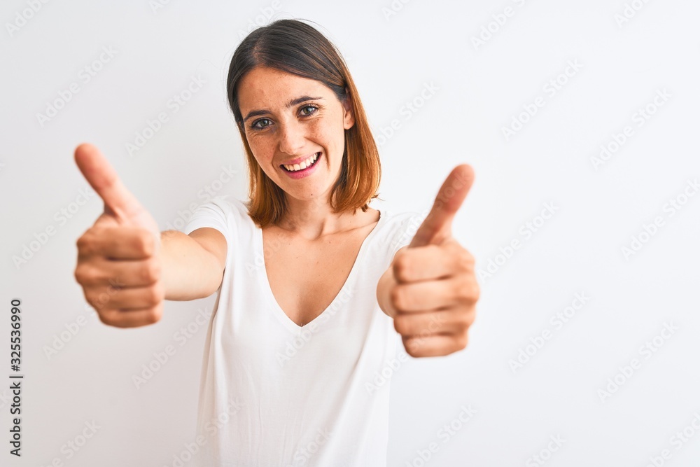 Beautiful redhead woman wearing casual white t-shirt over isolated background approving doing positive gesture with hand, thumbs up smiling and happy for success. Winner gesture. Beautiful redhead woman wearing casual white t-shirt over isolated background approving doing positive gesture with hand, thumbs up smiling and happy for success. Winner gesture.