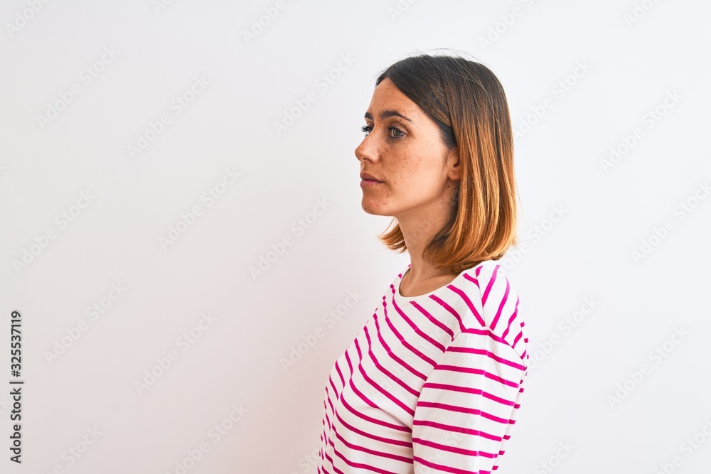 Beautiful redhead woman wearing casual striped pink t-shirt over isolated background looking to side, relax profile pose with natural face with confident smile. Beautiful redhead woman wearing casual striped pink t-shirt over isolated background looking to side, relax profile pose with natural face with confident smile.