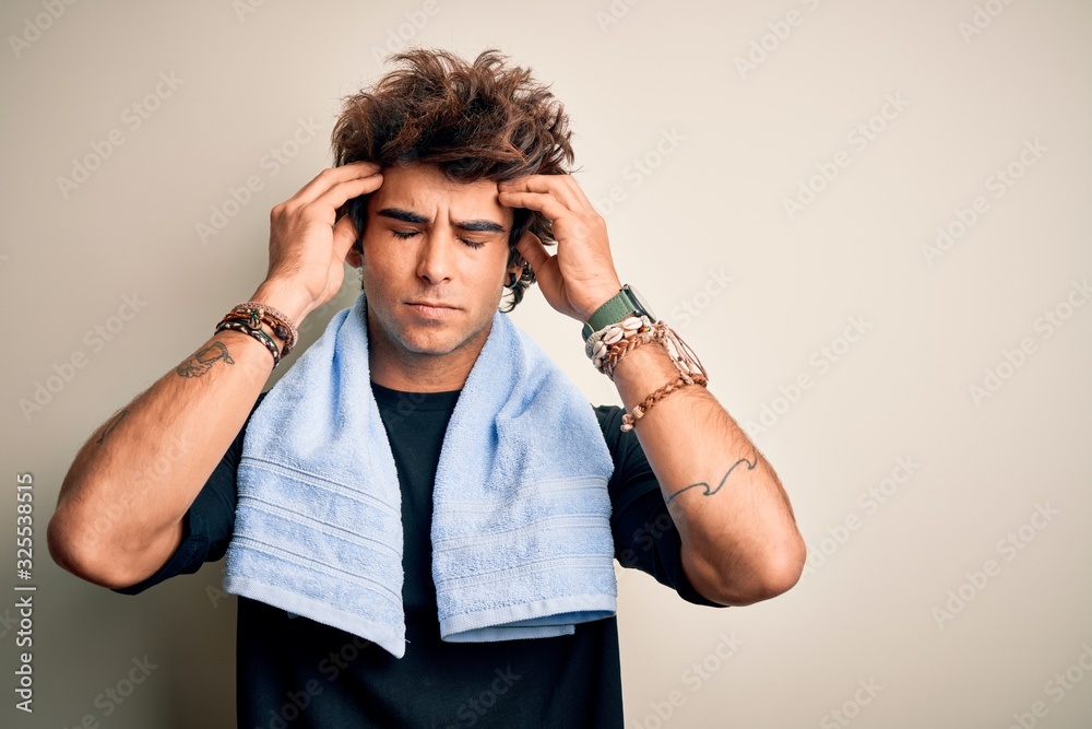 Young handsome sportsman wearing towel standing over isolated white background suffering from headache desperate and stressed because pain and migraine. Hands on head. Young handsome sportsman wearing towel standing over isolated white background suffering from headache desperate and stressed because pain and migraine. Hands on head.