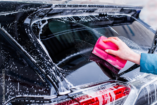 Girl cleaning automobile with sponge at car wash, car washing © FakeMoon