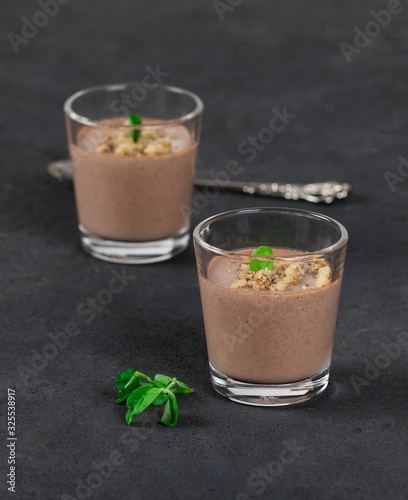 Chocolate nut jelly in a glass on a dark background.