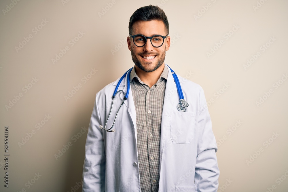 Young doctor man wearing glasses, medical white robe and stethoscope over isolated background with a happy and cool smile on face. Lucky person. Young doctor man wearing glasses, medical white robe and stethoscope over isolated background with a happy and cool smile on face. Lucky person.