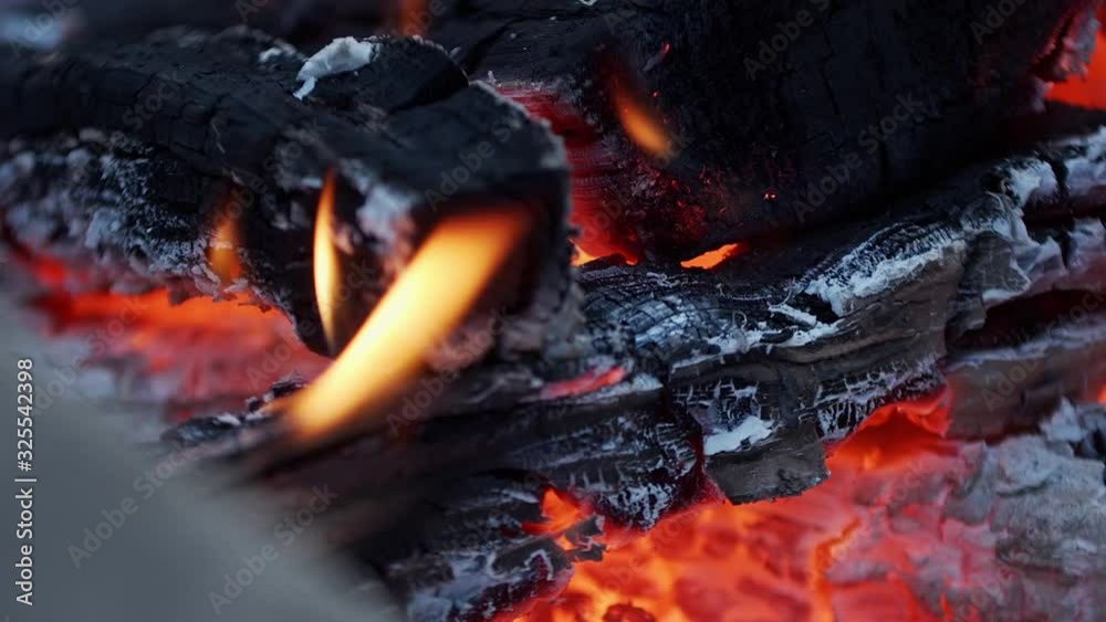 Campfire burned up wood with embers glowing and small flames Campfire burned up wood with embers glowing and small flames