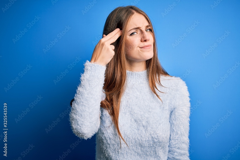Young beautiful redhead woman wearing casual sweater over isolated blue background Shooting and killing oneself pointing hand and fingers to head like gun, suicide gesture. Young beautiful redhead woman wearing casual sweater over isolated blue background Shooting and killing oneself pointing hand and fingers to head like gun, suicide gesture.