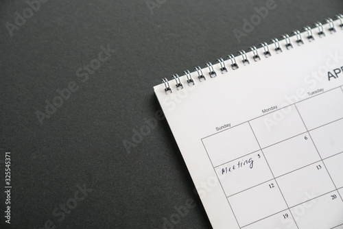 White clean calendar on black background with copy space. Words. meeting written on a date. Business meeting and schedule concept.