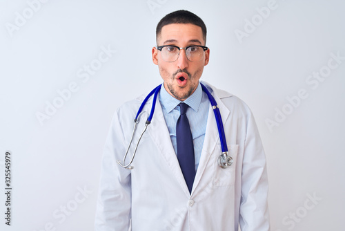 Young doctor man wearing stethoscope over isolated background afraid and shocked with surprise and amazed expression, fear and excited face.