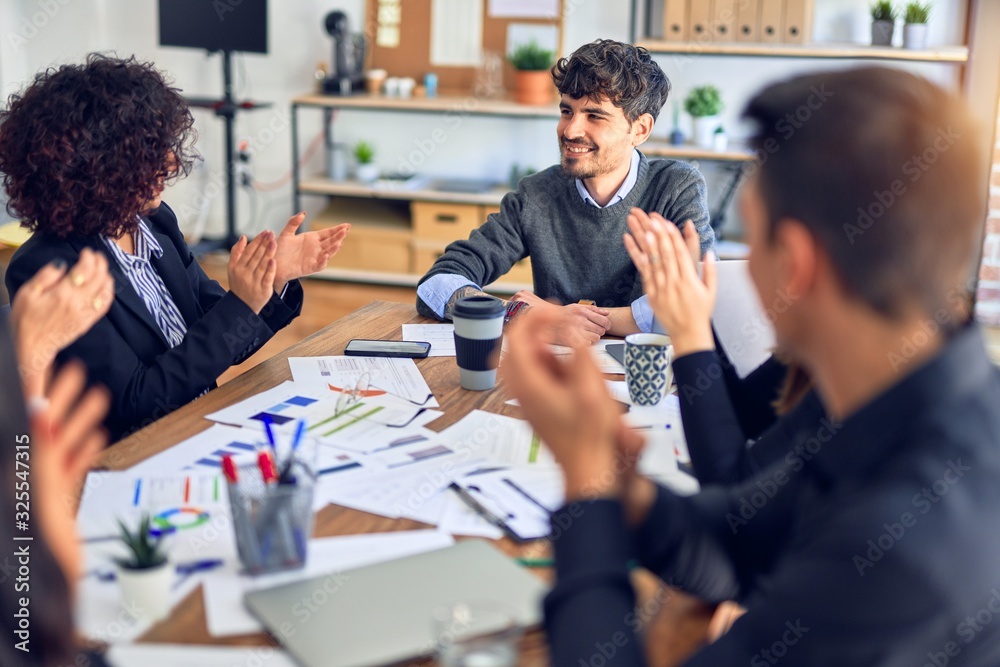 Group of business workers smiling happy and confident. Working together with smile on face applauding one of them at the office Group of business workers smiling happy and confident. Working together with smile on face applauding one of them at the office