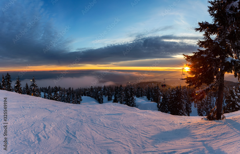 Seymour Mountain, North Vancouver, British Columbia, Canada. Panoramic View of Snowy runs on a ski resort during a sunny and cloudy winter sunset.