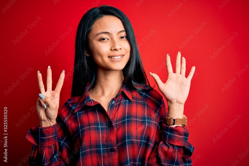 Young beautiful chinese woman wearing casual shirt over isolated red background showing and pointing up with fingers number eight while smiling confident and happy.