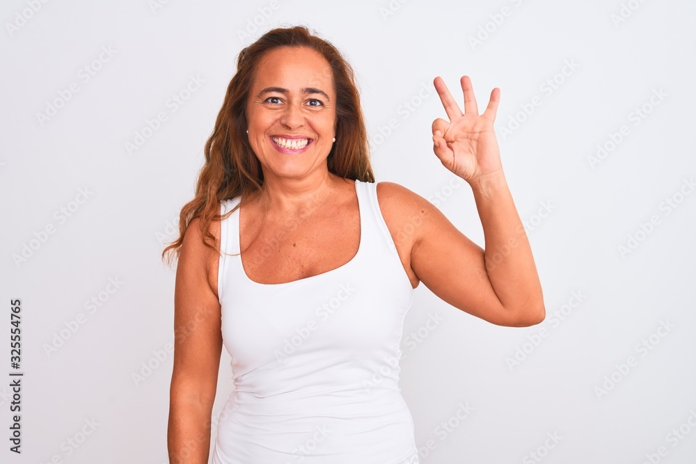 Middle age mature woman standing over white isolated background smiling positive doing ok sign with hand and fingers. Successful expression.