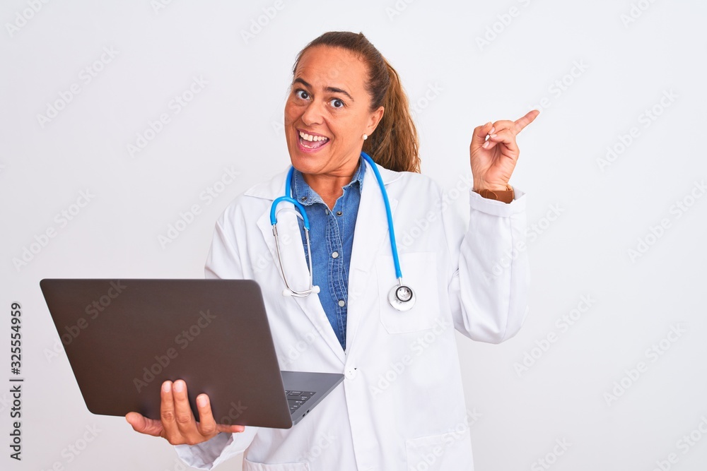 Middle age mature doctor woman holding computer laptop over isolated background very happy pointing with hand and finger to the side Middle age mature doctor woman holding computer laptop over isolated background very happy pointing with hand and finger to the side