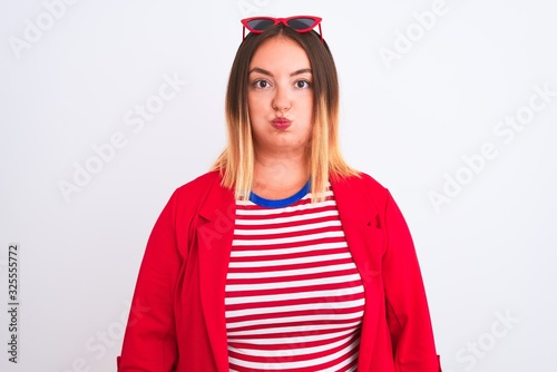 Young beautiful woman wearing striped t-shirt and jacket over isolated white background puffing cheeks with funny face. Mouth inflated with air, crazy expression.
