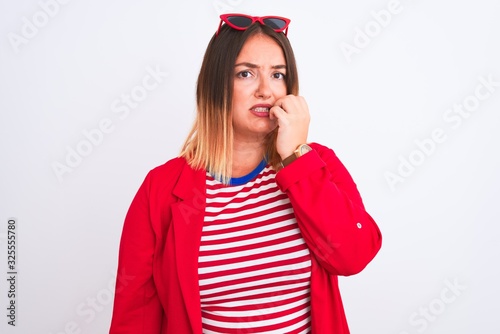 Young beautiful woman wearing striped t-shirt and jacket over isolated white background looking stressed and nervous with hands on mouth biting nails. Anxiety problem.