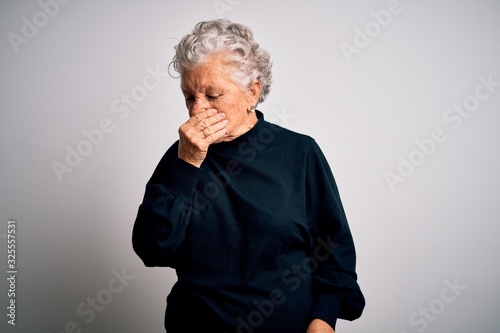 Senior beautiful woman wearing casual black sweater standing over isolated white background smelling something stinky and disgusting, intolerable smell, holding breath with fingers on nose. Bad smell
