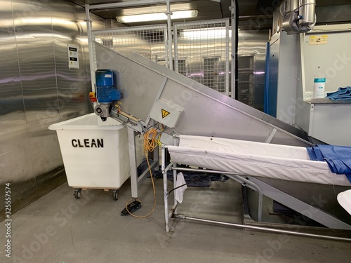 Laundry crew are working on the cruise ship. Huge operation on a luxury vessel. White trolley. Staff is wearing a professional uniform.