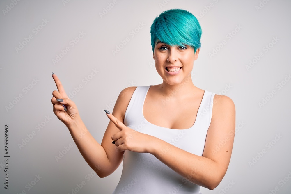 Young beautiful woman with blue fashion hair wearing casual t-shirt over white background smiling and looking at the camera pointing with two hands and fingers to the side.