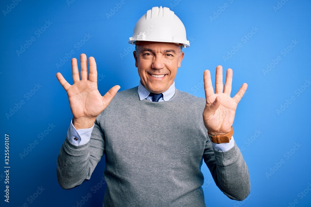 Middle age handsome grey-haired engineer man wearing safety helmet over blue background showing and pointing up with fingers number nine while smiling confident and happy. Middle age handsome grey-haired engineer man wearing safety helmet over blue background showing and pointing up with fingers number nine while smiling confident and happy.