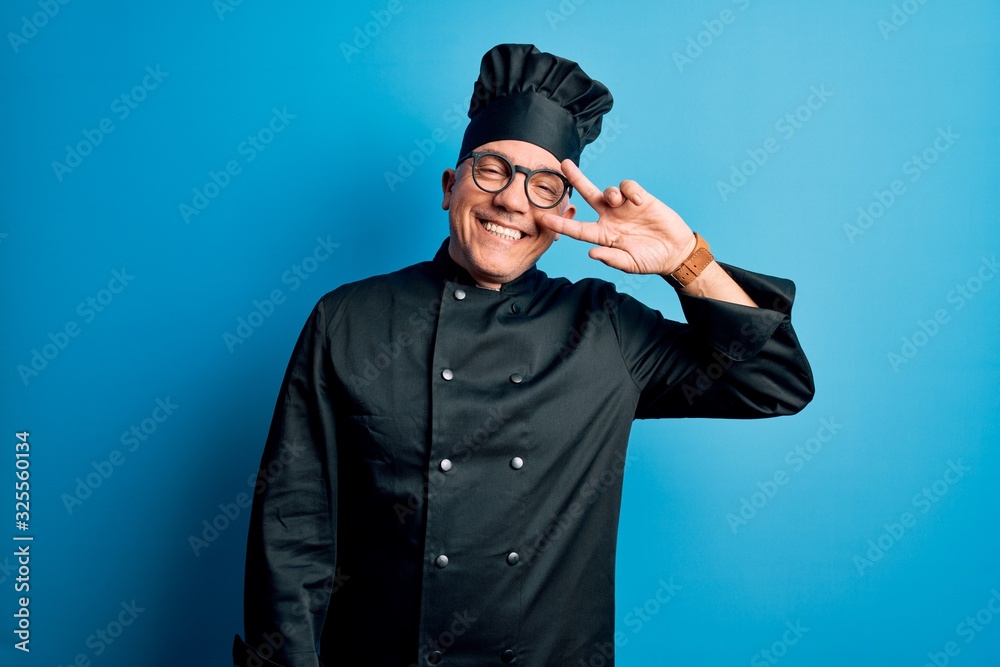 Middle age handsome grey-haired chef man wearing cooker uniform and hat Doing peace symbol with fingers over face, smiling cheerful showing victory Middle age handsome grey-haired chef man wearing cooker uniform and hat Doing peace symbol with fingers over face, smiling cheerful showing victory