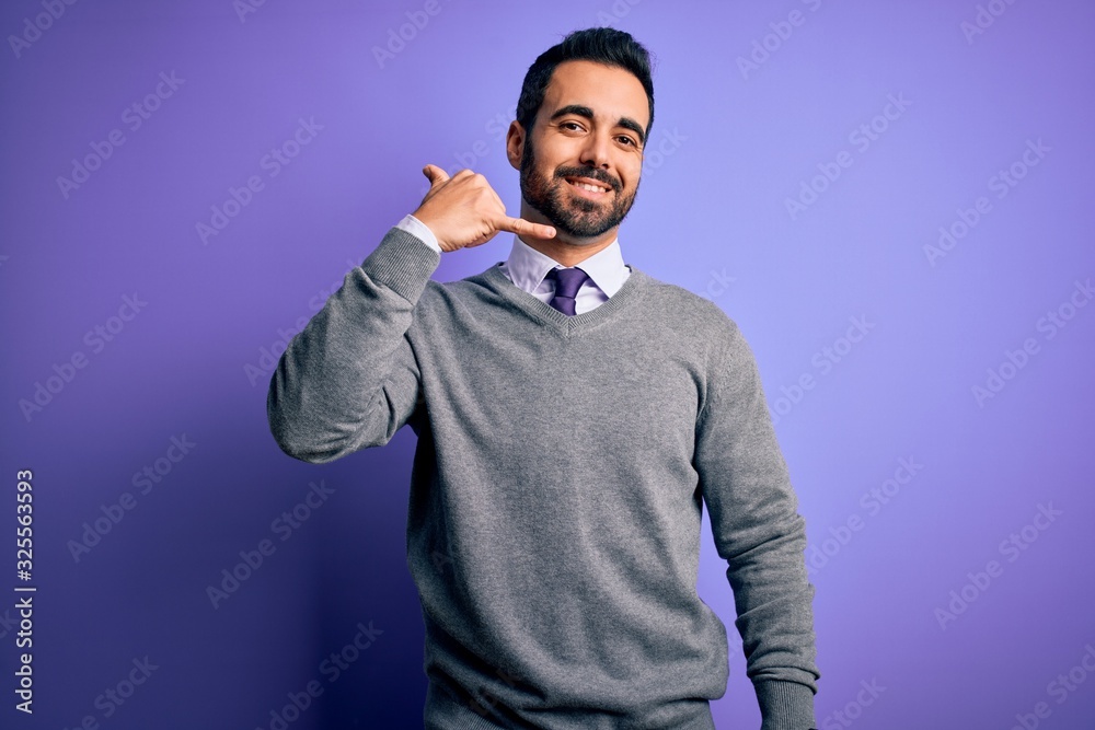 Handsome businessman with beard wearing casual tie standing over purple background smiling doing phone gesture with hand and fingers like talking on the telephone. Communicating concepts. Handsome businessman with beard wearing casual tie standing over purple background smiling doing phone gesture with hand and fingers like talking on the telephone. Communicating concepts.