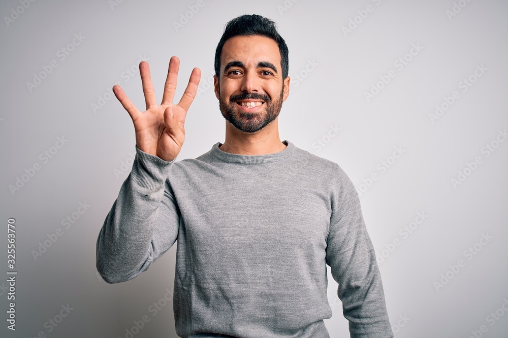 Young handsome man with beard wearing casual sweater standing over white background showing and pointing up with fingers number four while smiling confident and happy. Young handsome man with beard wearing casual sweater standing over white background showing and pointing up with fingers number four while smiling confident and happy.