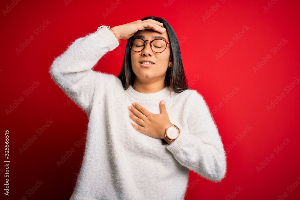 Young beautiful asian woman wearing casual sweater and glasses over red background Touching forehead for illness and fever, flu and cold, virus sick Young beautiful asian woman wearing casual sweater and glasses over red background Touching forehead for illness and fever, flu and cold, virus sick