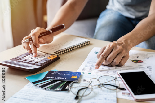 Young woman checking bills, taxes, bank account balance and calculating credit card expenses at home photo