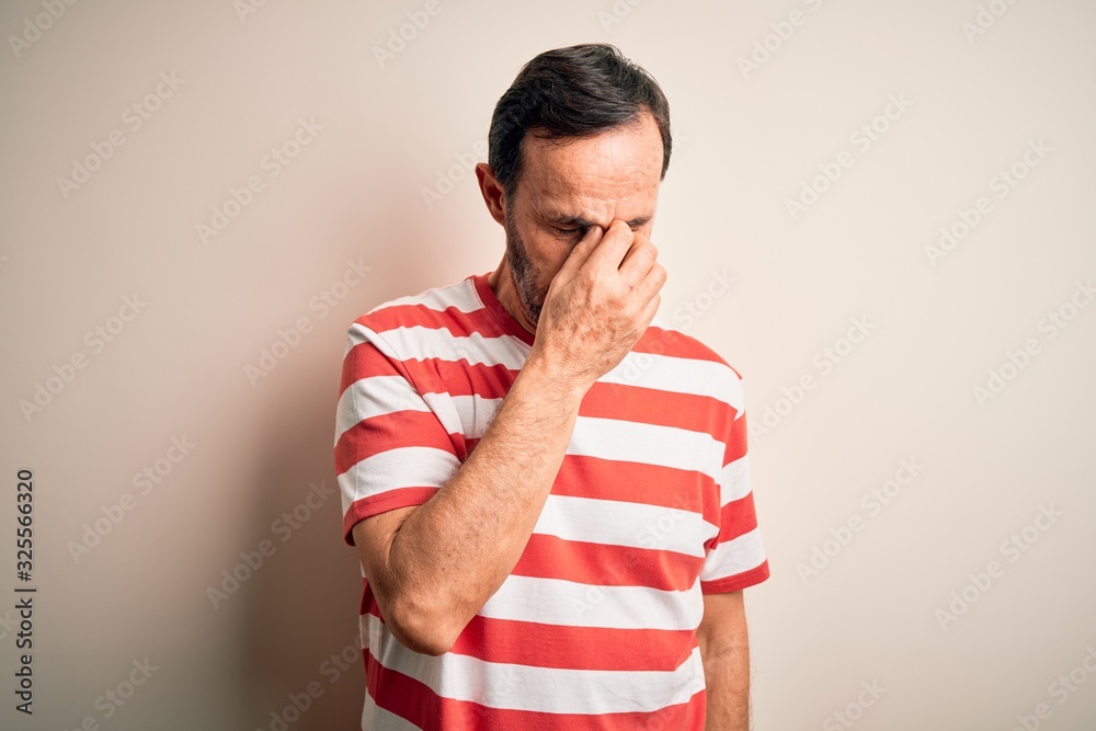 Middle age hoary man wearing casual striped t-shirt standing over isolated white background tired rubbing nose and eyes feeling fatigue and headache. Stress and frustration concept. Middle age hoary man wearing casual striped t-shirt standing over isolated white background tired rubbing nose and eyes feeling fatigue and headache. Stress and frustration concept.