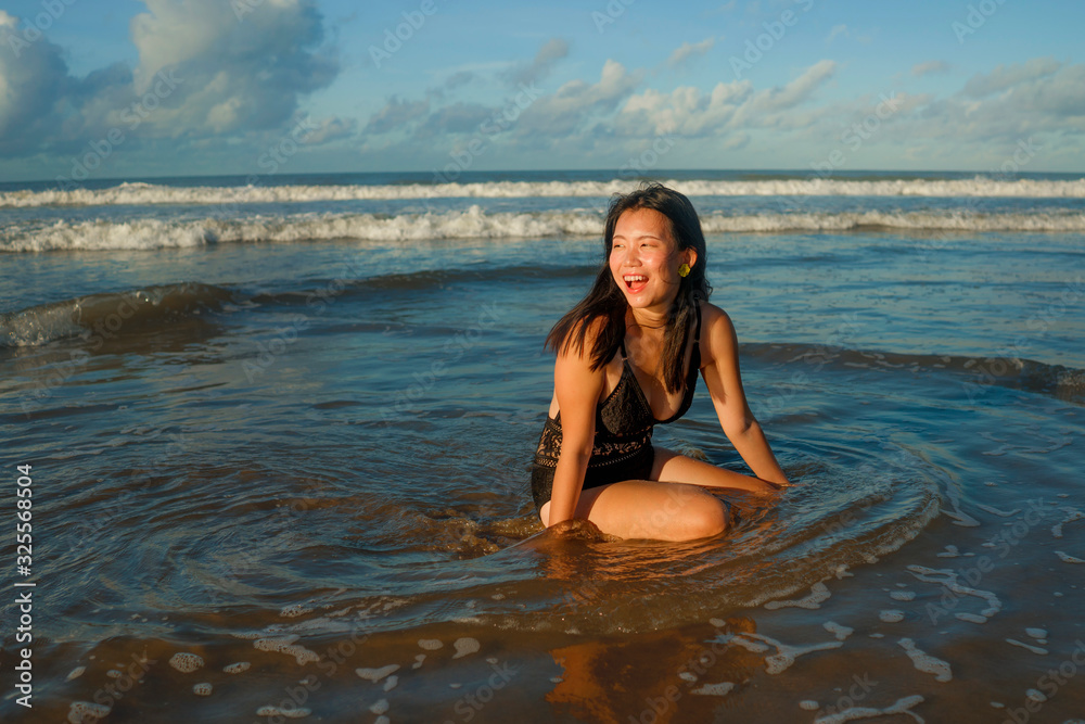 natural lifestyle portrait of young attractive and happy Asian Korean woman in swimsuit having fun at beautiful beach paradise feeling relaxed and cheerful enjoying holidays carefree