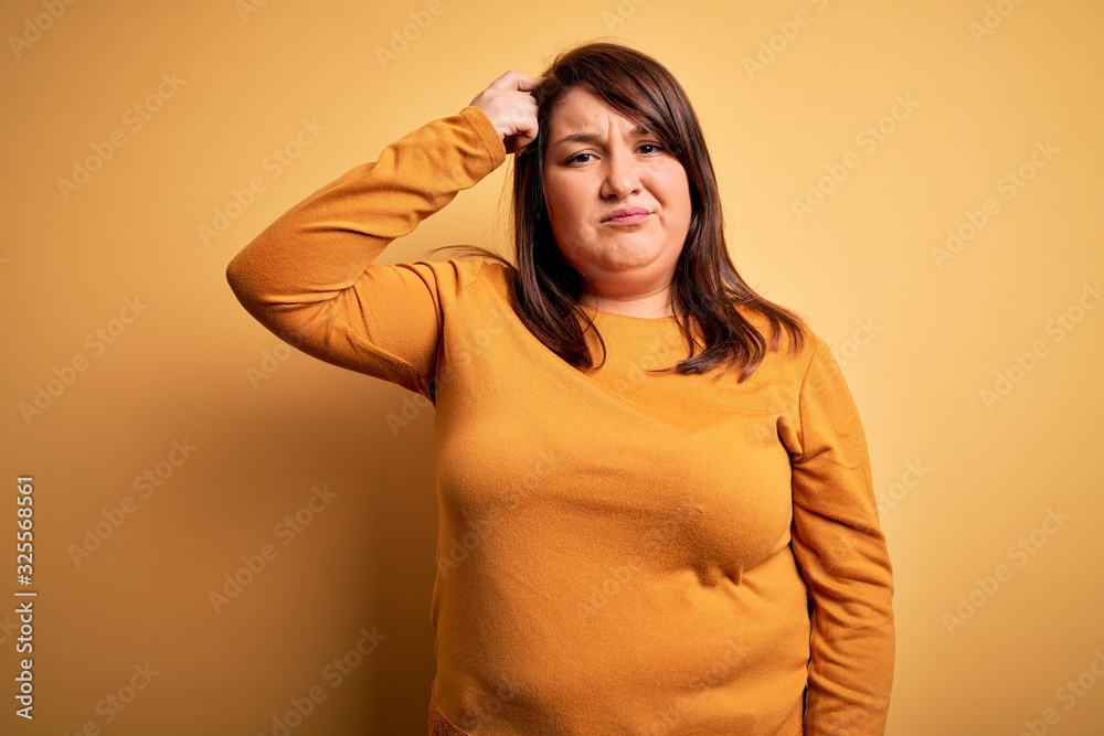Beautiful brunette plus size woman wearing casual sweater over isolated yellow background worried and stressed about a problem with hand on forehead, nervous and anxious for crisis Beautiful brunette plus size woman wearing casual sweater over isolated yellow background worried and stressed about a problem with hand on forehead, nervous and anxious for crisis