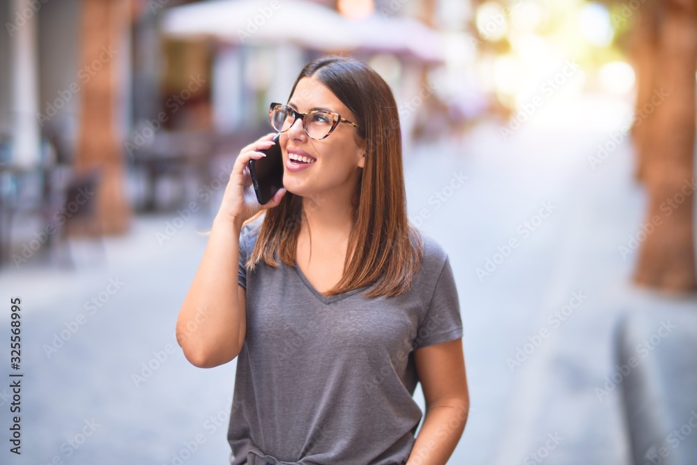 Young beautiful woman smiling happy and confident. Standing with smile on face talking by the smartphone at town street Young beautiful woman smiling happy and confident. Standing with smile on face talking by the smartphone at town street