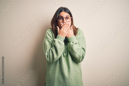 Young beautiful woman wearing casual sweater standing over isolated white background shocked covering mouth with hands for mistake. Secret concept.