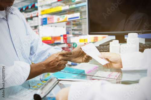 Blur image senior sick man stood to buy medicines from the female pharmacist in the pharmacy to cure the illness : Blurred background