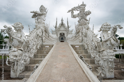 Beautiful architecture of White temple (Wat Rong Khun)  in Chiang Rai province of Thailand in the cloudy day. The Wat Rong Khun was designed by Chalermchai Kositpipat, a famous Thai visual artist.