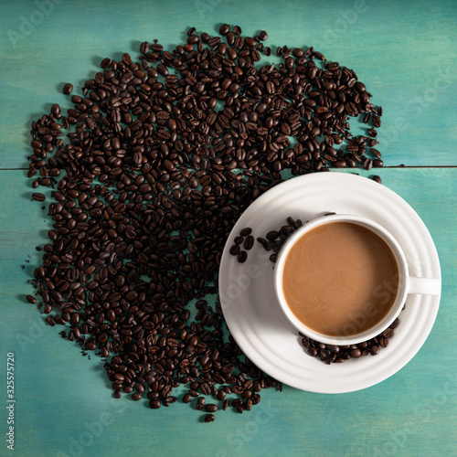 Overhead of coffee cup on saucer srrounded by coffee beans photo