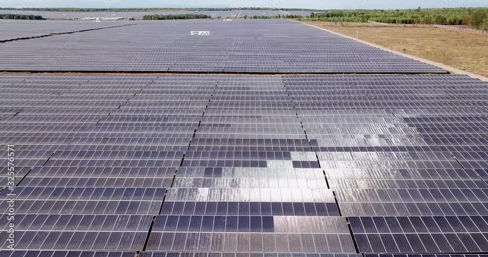 endless fields of solar panels in Vietnam, during a sunny day. elevated view panning left with visible sun reflection endless fields of solar panels in Vietnam, during a sunny day. elevated view panning left with visible sun reflection