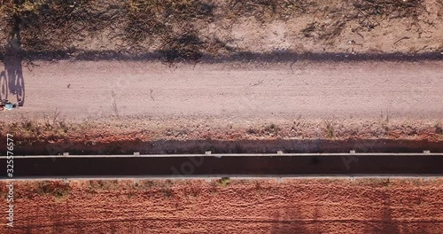 closeup top view of a motorbike driving trough a deserted red sand road casting a shadow photo