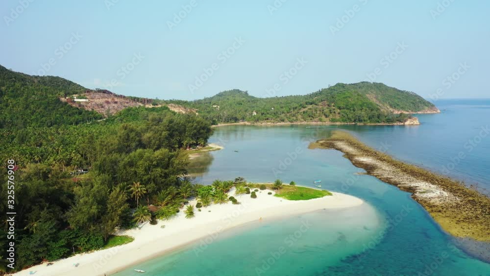 Thailand, Aerial - low rounded hills on the coast of the tropical island. boats floating near the sandy beach with palms